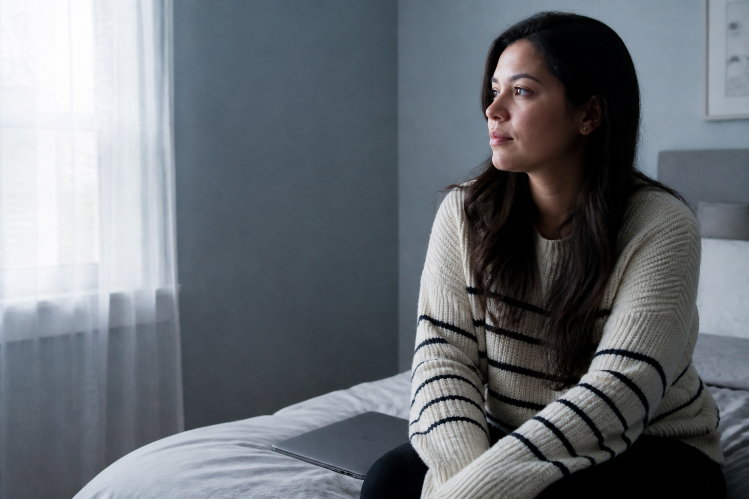 Pensive woman looking toward a window, composed — not sad